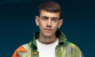 ששון שאולוב במקטורן צבעוני, ירוק, כתום, אפור וכפתור כתום.