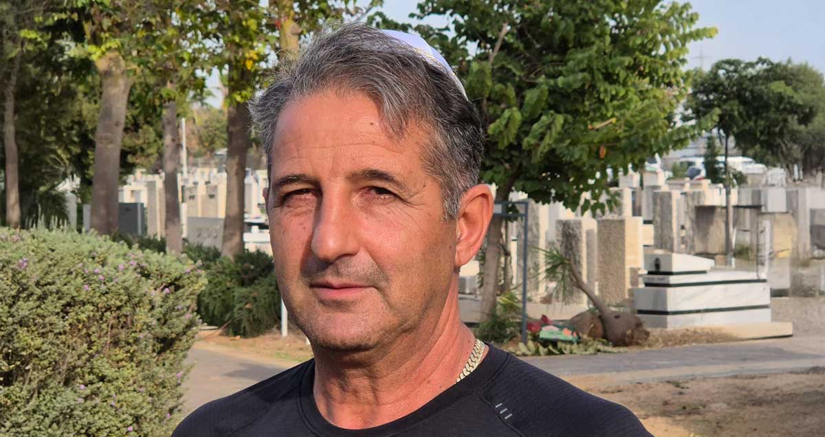 אבי עמרני הבעלים של עמרני חומרי בניין ברמת השרון, עם כיפה, על רקע בית עלמין.