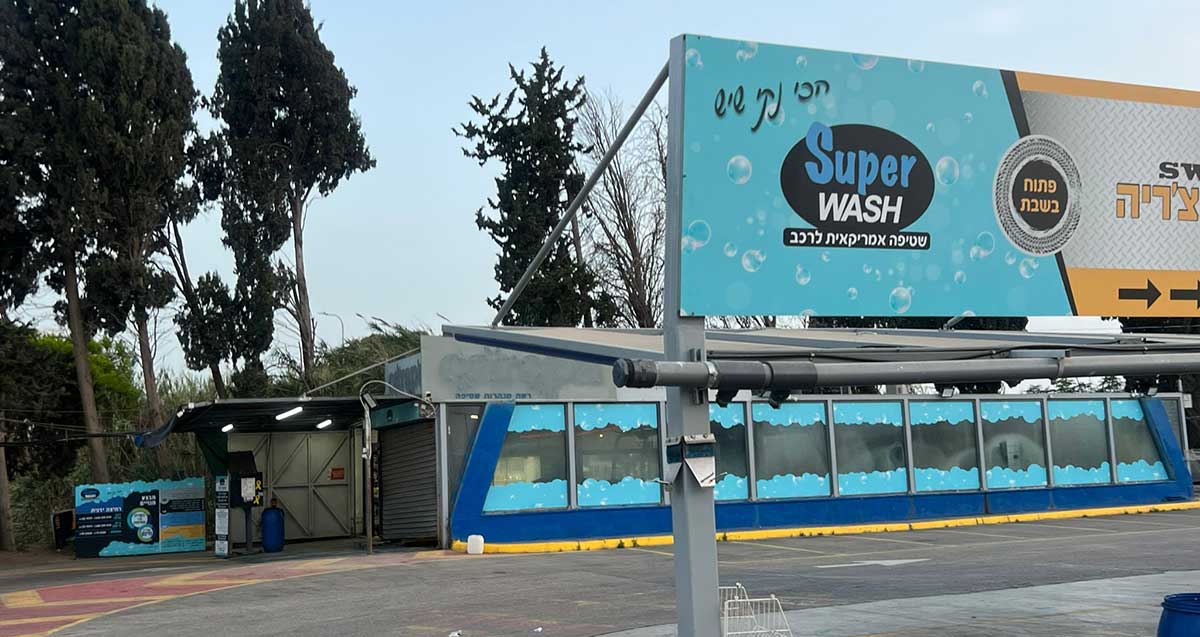 העסק לשטיפת מכוניות בשדרות שבעת הכוכבים בהרצליה. תמונה של מבנה השטיפה כאשר הוא סגור. שלט גדול לפני העסק ושמו באנגלית: Super WASH. ובעברית כיתוב: הכי נקי שיש, פתוח בשבת.