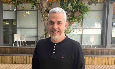 עידו לביא, צילום פלג גוף עליון. מאחוריו דק וחנויות