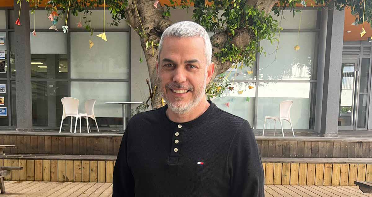 עידו לביא, צילום פלג גוף עליון. מאחוריו דק וחנויות