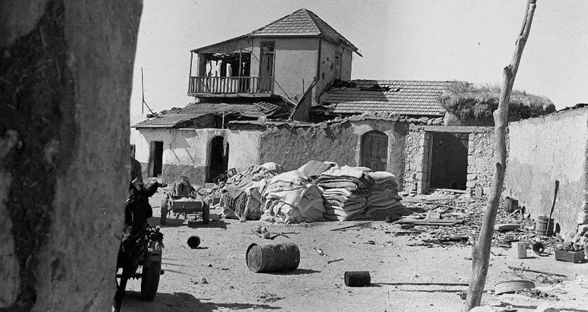 כפר סאבא הערבית. בית עזוב, מאבנים וציפוי חימר, שחציו קומה אחת וחציו שתי קומות, עם גגות רעפים. בחצר עגלות עם חמורים. וערימות של שקים.