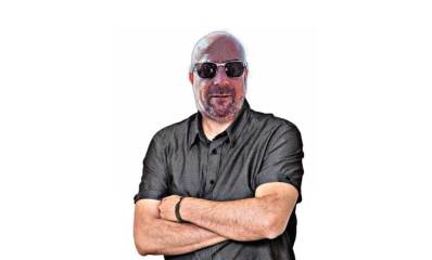 איור של מיקי מחבובי עומד בשילוב ידיים ומרכיב משקפי שמש כהות.