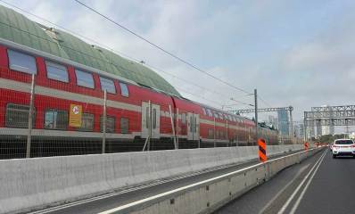 רכבת בנתיבי איילון, במרכז, בין שני המסלולים של כלי הרכב, ומעליה כבלי החשמל.