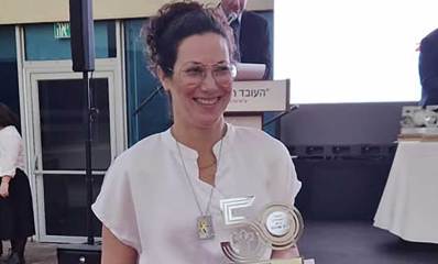 יעל צחור פיכמן זוכת "אות הנשיא" לעובדים מצטיינים, עם אות הצטיינות בצורת המספר חמישים.