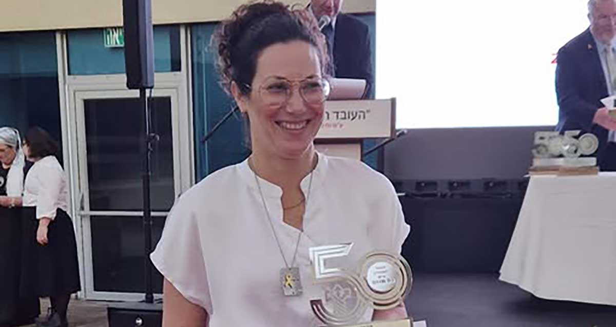 יעל צחור פיכמן זוכת "אות הנשיא" לעובדים מצטיינים, עם אות הצטיינות בצורת המספר חמישים.