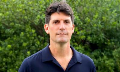 ד"ר ארד אדר. תמונה של פלג גוף עליון על רקע של צמחייה. חומה וצמחייה.