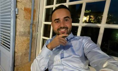 עו"ד דניאל אוטמזגין יושב ויד אחת לפני הסנטר. מאחוריו חלון עם ריבועי זכוכית.