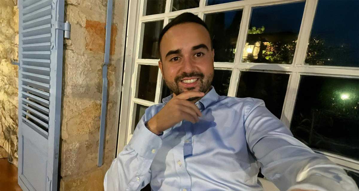 עו"ד דניאל אוטמזגין יושב ויד אחת לפני הסנטר. מאחוריו חלון עם ריבועי זכוכית.