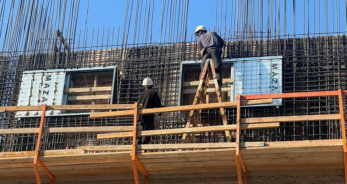 פועל על סולם בעבודת בגובה רב באתר בניית בית ספר