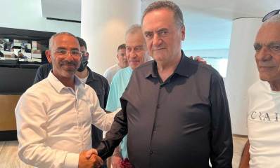 ישראל כץ ורפי קדושים ועוד מספר אנשים עומדים באולם. ישראל ורפי לוחצים יד.