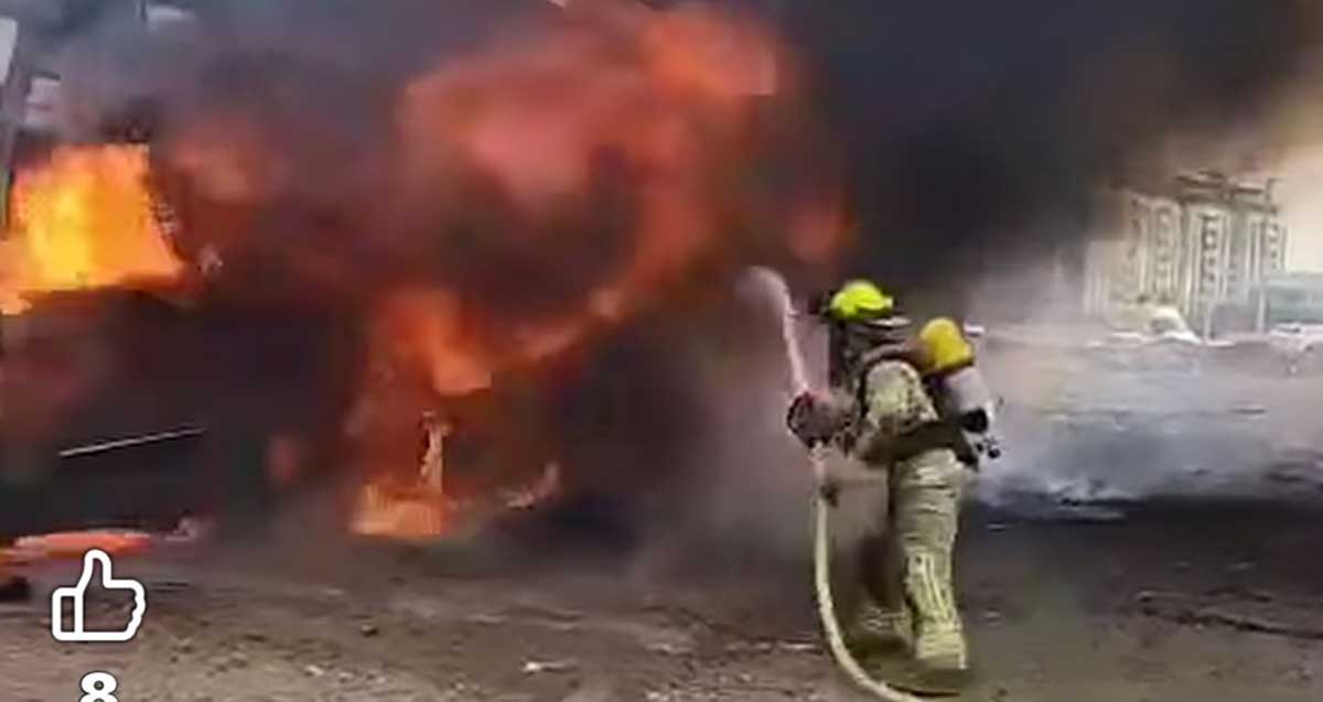 נפילת טיל בחניון אוטובוסים ליד שכונת מגורים בהרצליה. כבאי עם זרנוק מים מכבה את האש הגדולה.