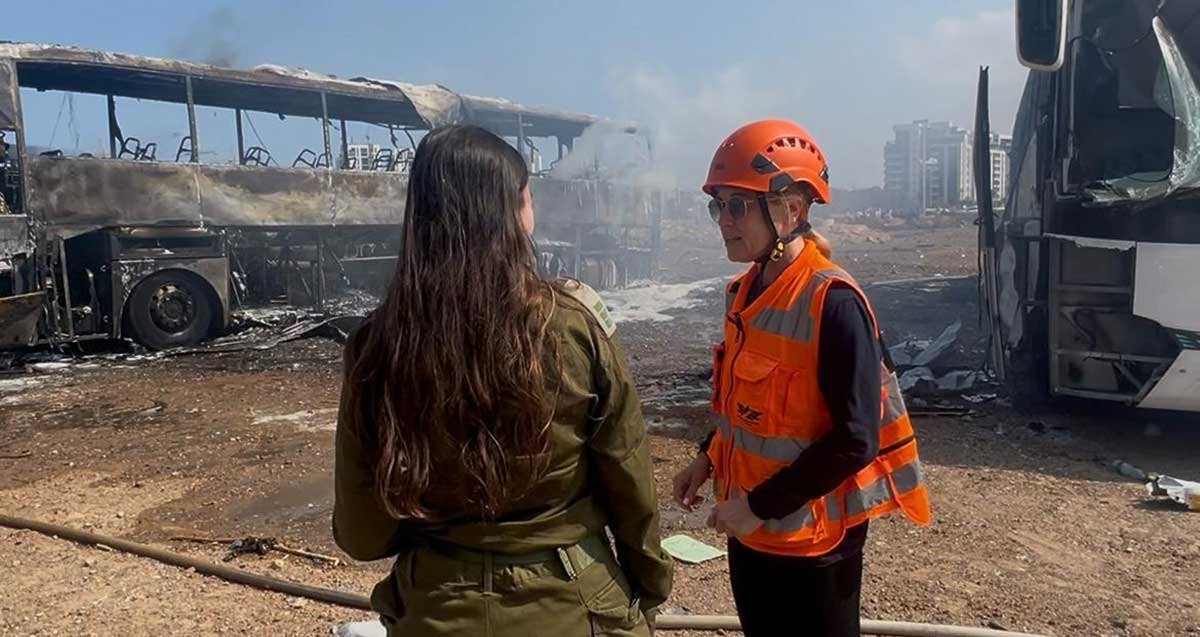 זירת נפילת הטיל האיראני בהרצליה בבוקר 17 ביוני 2025. כבאית וקצינת צה"ל ליד אוטובוס שרוף.