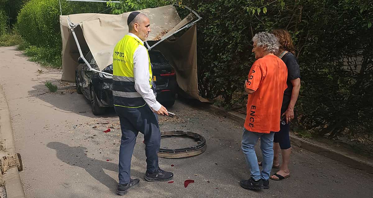 סגן ראש עיריית רמת השרון יעקב קורצקי בזירת נפילת שבר טיל איראני שיורט ברמת השרון, עם זוג אנשים, ליד רכב חונה שהסככה שלו מבד נפגעה.