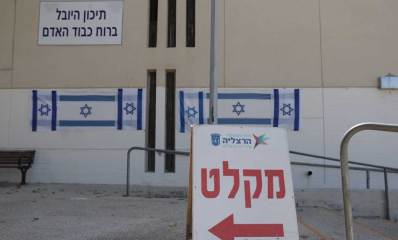 מקלט ציבורי בבית ספר. שלט בחוץ עם חץ שמאלה וכיתוב: מקלט. על קיר הבניין הכיתוב: תיכון היובל ברוח כבוד האדם.