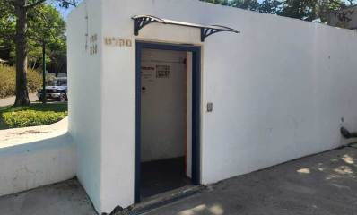 מקלט ציבורי על פני הקרקע. ליד הכניסה כיתוב: מקלט. מעבר לדלת יש שילוט ימינה למקלט, ושלט של עיריית הרצליה.
