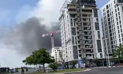 נפילת טיל בהרצליה. עשן עולה מאחורי מנוף של בניין בבניה ובניינים וכיכר בחזית