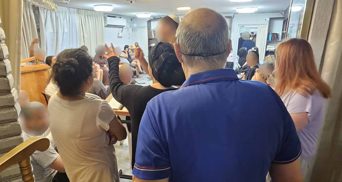 תושבים במקלט בהרצליה. המקלט צפוף ועמוס בספריות עם ספרי קודש