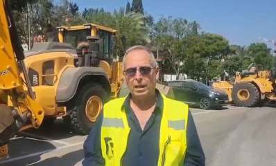 איציק רוכברגר, ראש העיר של רמת השרון עומד עם ווסט זוהר באמצע כביש. מאחוריו טרקטורים של JCB