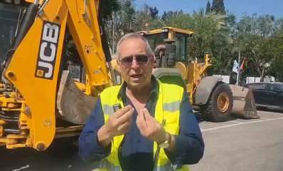 איציק רוכברגר, ראש העיר של רמת השרון עומד עם ווסט זוהר באמצע כביש. מאחוריו טרקטורים של JCB