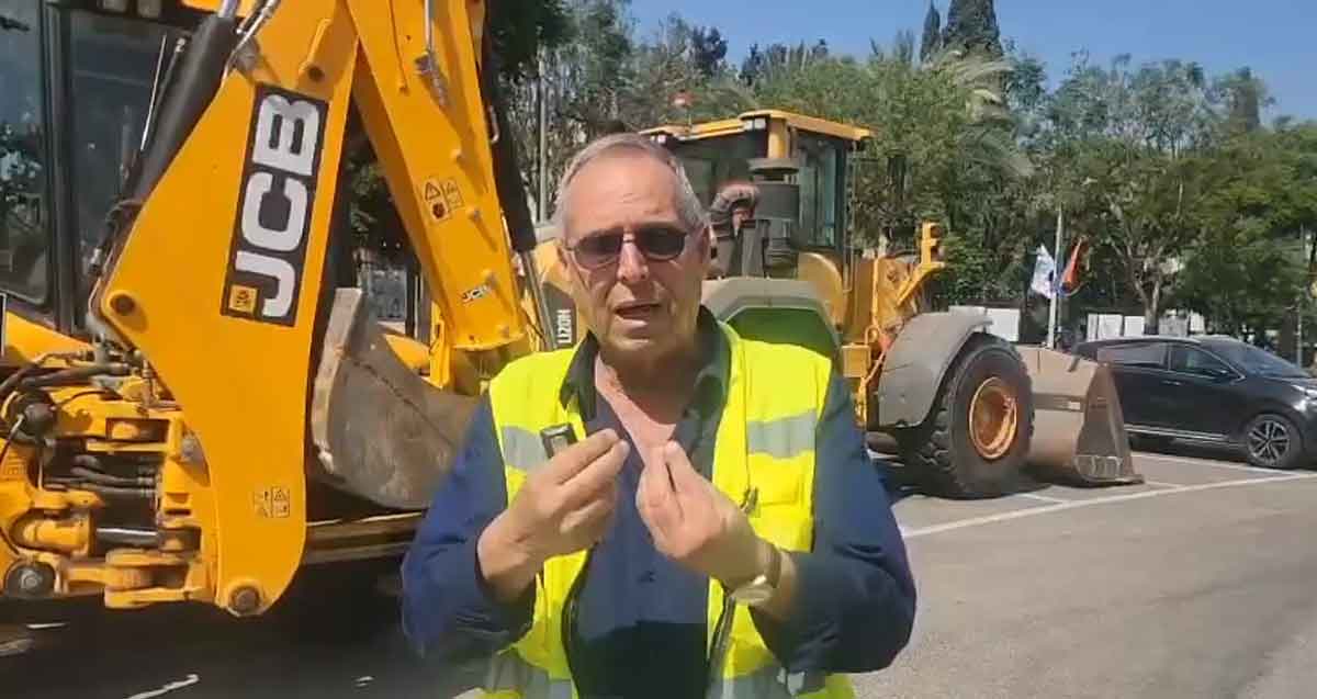 איציק רוכברגר, ראש העיר של רמת השרון עומד עם ווסט זוהר באמצע כביש. מאחוריו טרקטורים של JCB