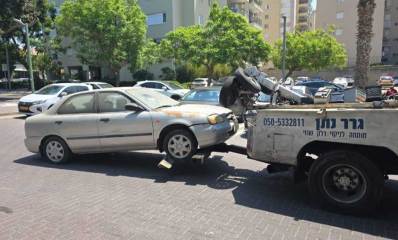 עיריית הרצליה מפנה רכבים נטושים. מכונית גרר גוררת רכב פרטי. על מכונית הגרר כיתוב: גרר נתן