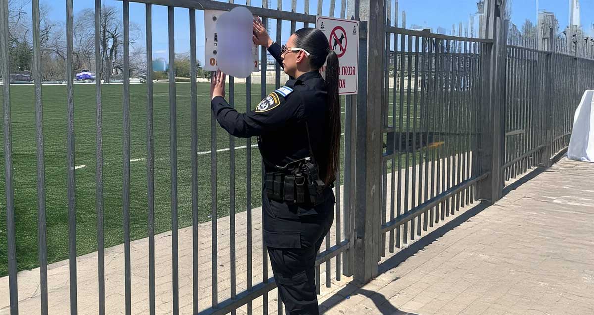 צו סגירה למתקן האימונים עמנואל שפר ברמת השרון. שוטרת תולה את הצו על גדר המגרש.