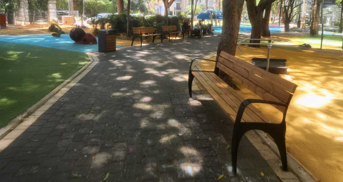 גינת הקוצר ברמת השרון. רחבה עם דשא. רחבה עם פסלים לילדים. רחבה עם משטח חול. ספסלים מעץ לאורך השביל, ועצים גדולים המשליכים צל.