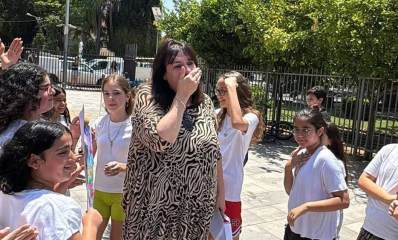 שורות של תלמידים בפרידה מרגשת בהוד השרון מהמנהלת חנה ענבר מילוא. חנה מכסה את פניה מהתרגשות ועוברת בינהן