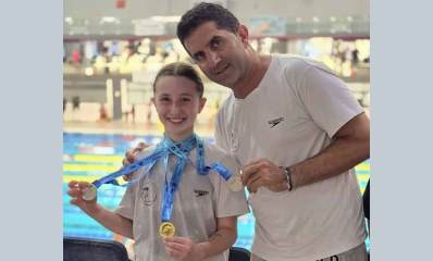 נוי גוטפריד מציגה את המדליות בהן זכתה. אחת מזהב ושניים מכסף, על רקע הבריכה.