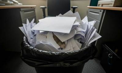 ניירות בפח אשפה בתוך שקית פלסטיק שחורה, במשרד.