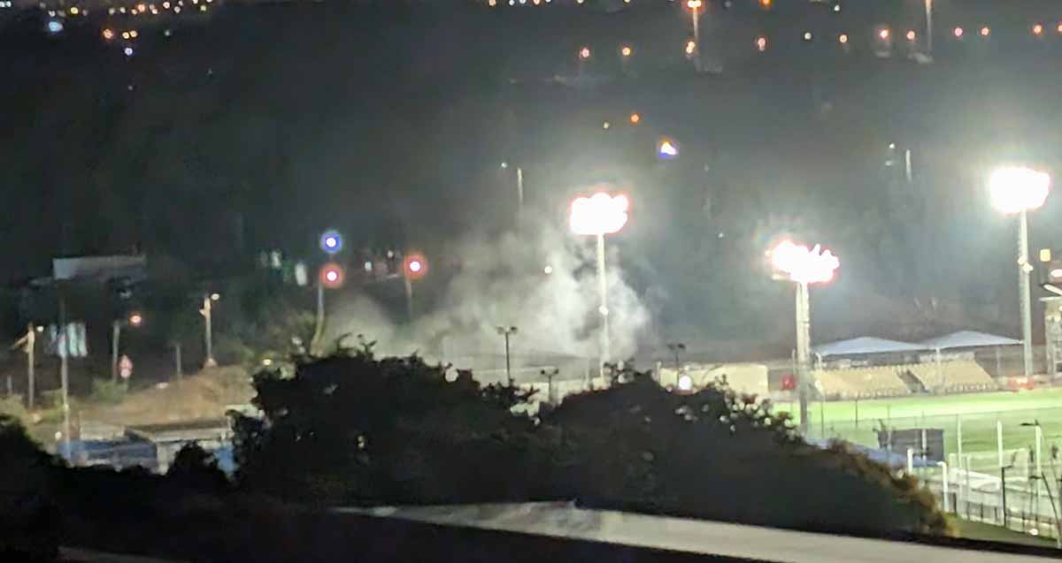 תאורה באצטדיון כדורגל, מאירה חלק מהמגרש. עשן עולה מאחת מפינותיו