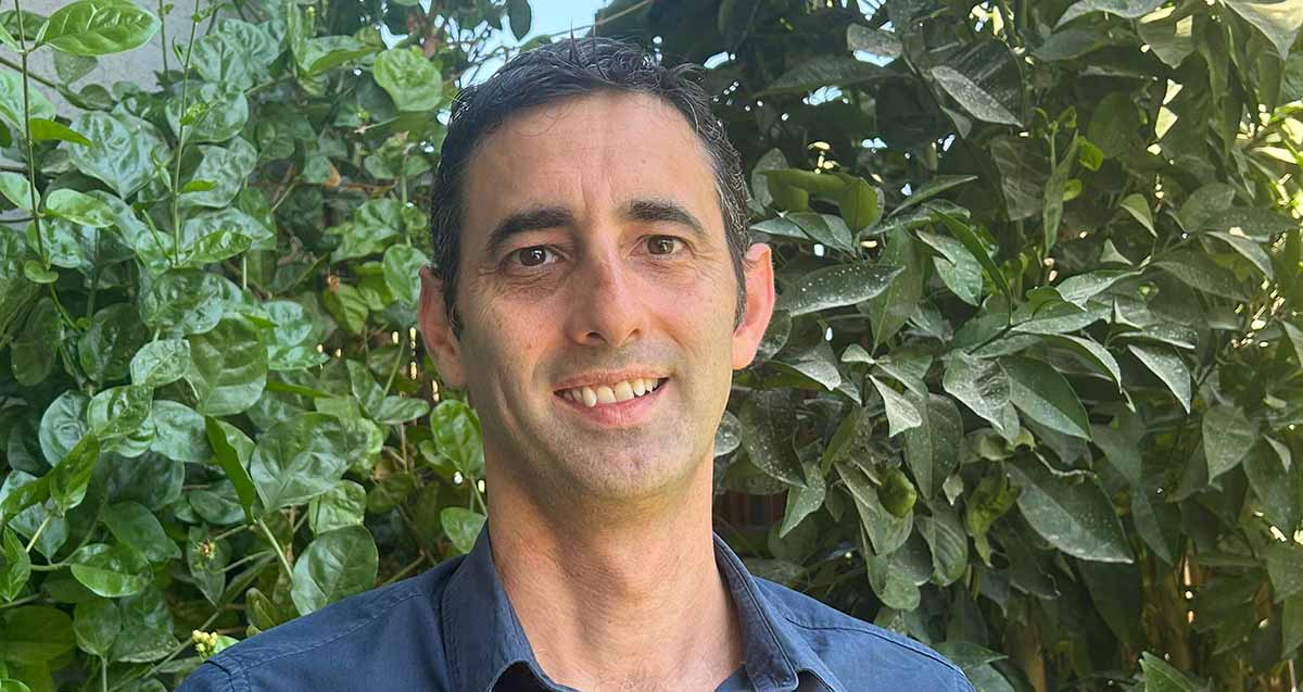 תמונת פנים של יאיר די סגני, מנהל בית הספר הנדיב. מאחוריו צמחייה