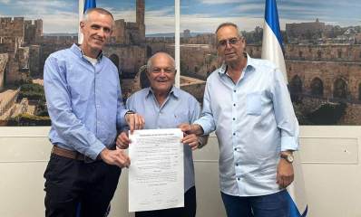 - איציק רוכברגר, שר השיכון חיים כץ וחשב רשות מקרקעי ישראל אוחזים בהסכם החתום. מאחוריהם תמונה של העיר העתיקה בירושלים