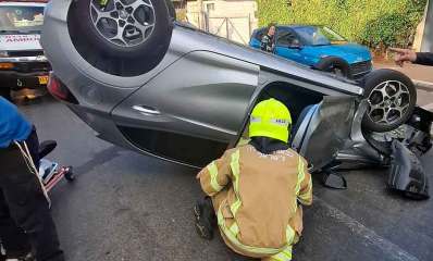 תאונה במורשה. מכונית פרטית הפוכה וליד דלת פתוחה כורע איש של כבאות והצלה לישראל.