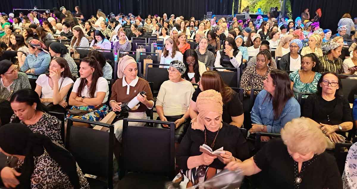 הכנס של תנועת אמונה. נשים יושבות בשורות באולם גדול.