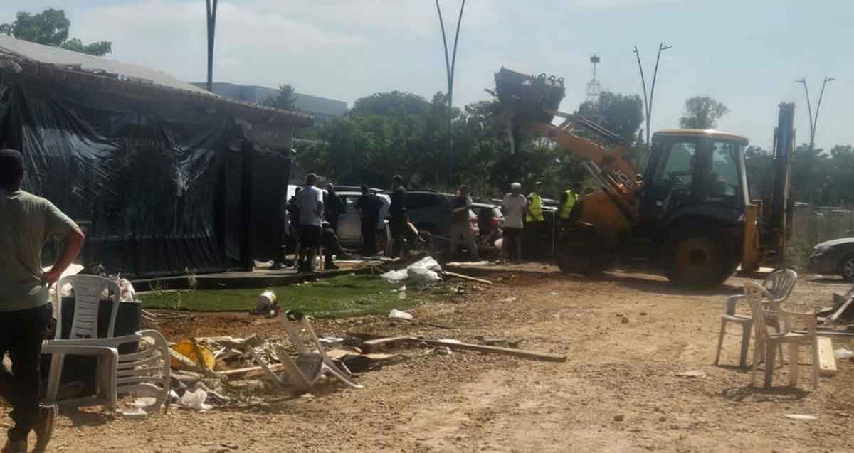 ביצוע צו הריסה של בנייה לא חוקית בעסק מזון בכניסה לבסיסי המודיעין. כלי הנדסי עם כף ליד העסק.