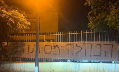 שלט בד תלוי על גדר תיכון גלילי בכפר סבא. בשלט כתוב: הנלה מסיתה. אין חפים מפשע