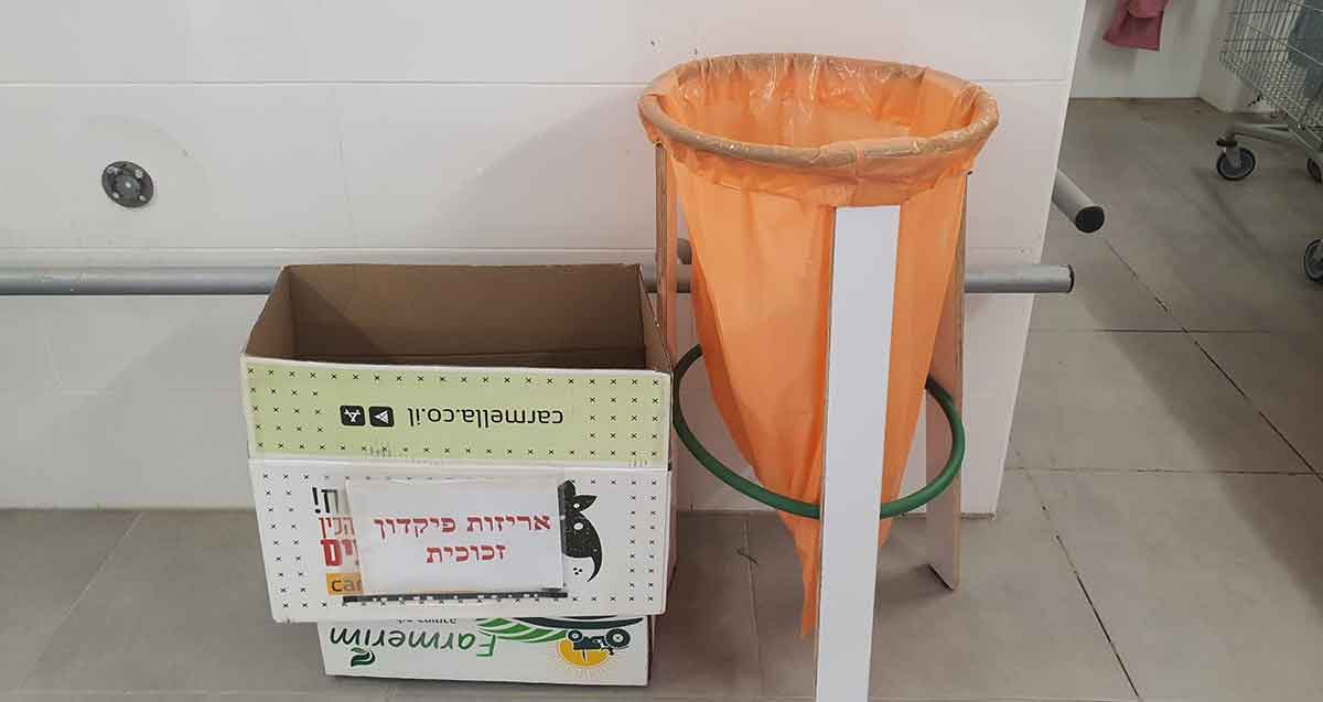 אריזות פיקדון זכוכית - הדגם הישן. מימין שקית פלסטיק כתומה בתוך מסגרת עגולה. משמאל קרטון עם שלט וכיתוב: אריזות פיקדון זכוכית.