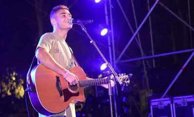 נועם חן שר ומנגן על גיטרה על במה מוארת בפארק הנצח ברמת השרון