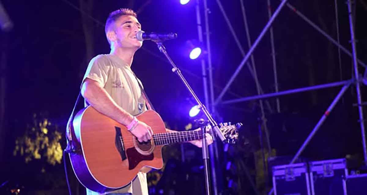 נועם חן שר ומנגן על גיטרה על במה מוארת בפארק הנצח ברמת השרון