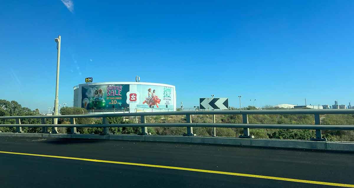 פי גלילות. בריכת מים עגולה ועליה פרסומות של סופר-פארם באנגלית: SUMMER SALE