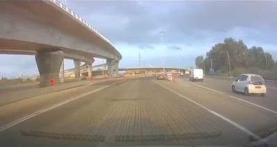 מכוניות נוסעות על כביש 5, ליד מחלף וגשרים. הכביש מקורצף ולא מסומן