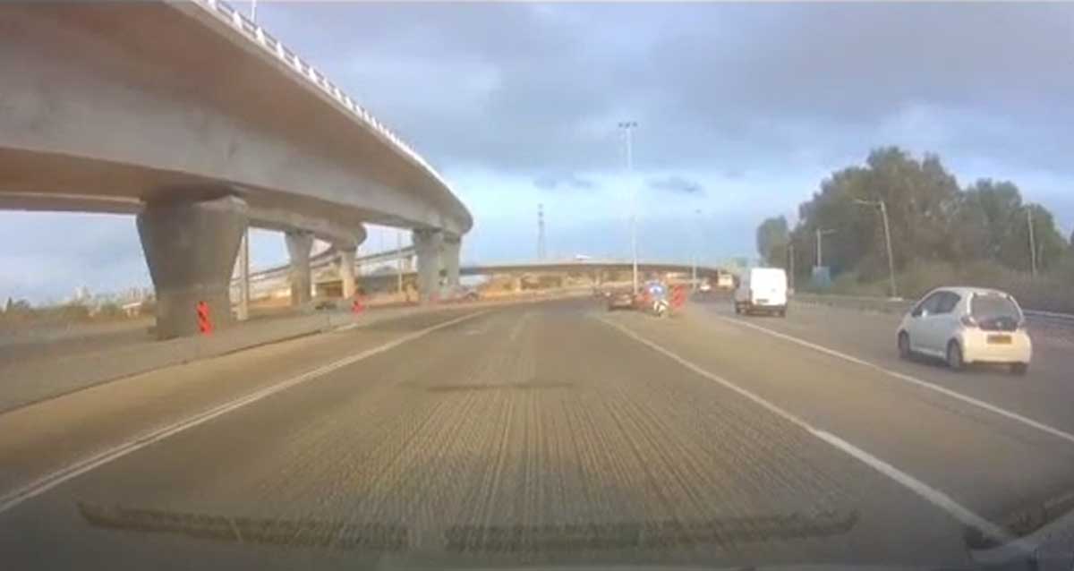 מכוניות נוסעות על כביש 5, ליד מחלף וגשרים. הכביש מקורצף ולא מסומן