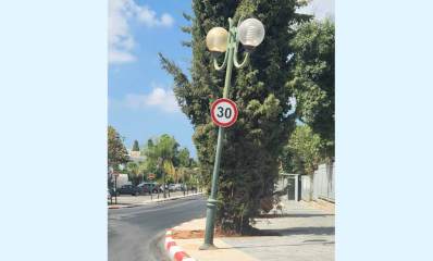 עמוד תאורה בסכנת נפילה צמוד לכיכר בית ספר השחר. על העמוד תלוי תמרור הגבלת מהירות ל 30