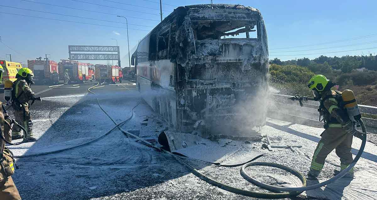 אוטובוס נשרף באיילון, כביש 20. אנשי כבאות והצלה עם זרנוקים מכבים את השריפה באוטובוס.