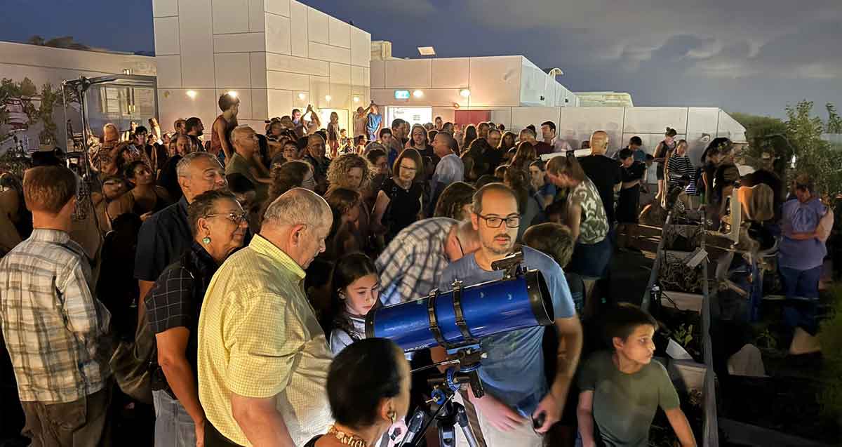 תושבי הרצליה על גג בניין מטאור. בחזית התמונה טלסקופ בצבע כחול. המון רב על הגג.