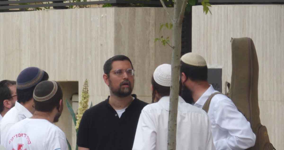 נתנאל סימן-טוב במשקפי ראייה, מוקף עם חמישה אנשים עם כיפות.