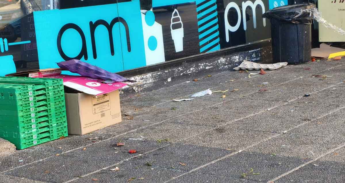 טשרניחובסקי בין ויצמן לששת הימים. קרטונים וארגזי פלסטיק ליד קיר עם הכיתוב באנגלית: am pm