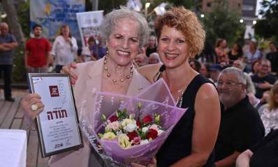 הוקרה למתנדבות ומתנדבים בהרצליה. שתי מתנדבות עם תעודה וזר פרחים. ברקע יושב קהל.